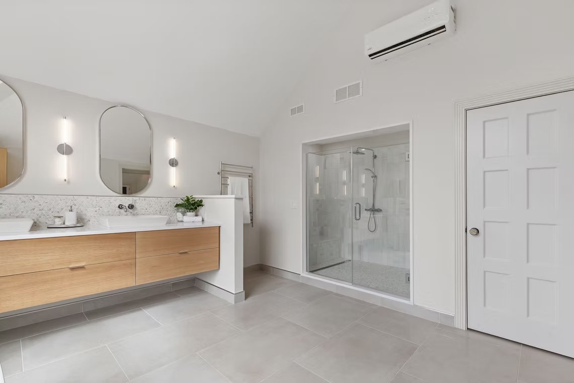 J & R bright bathroom with stone double vanity and oak cabinetry